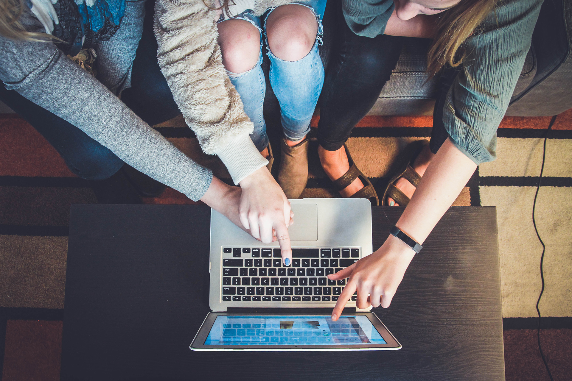 Three people working together on one laptop